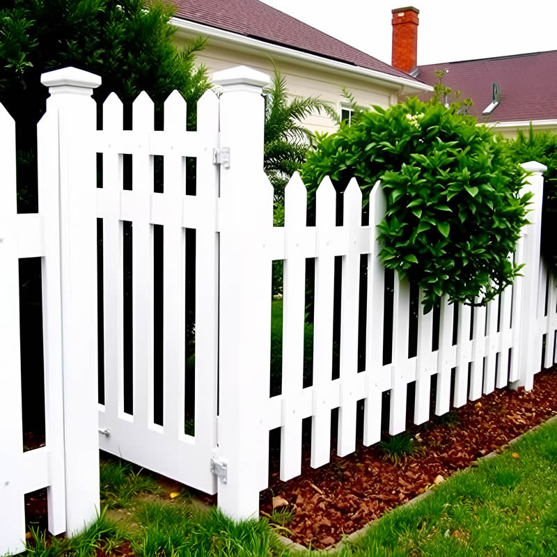 White vinyl picket fence with a matching gate beside a landscaped garden.