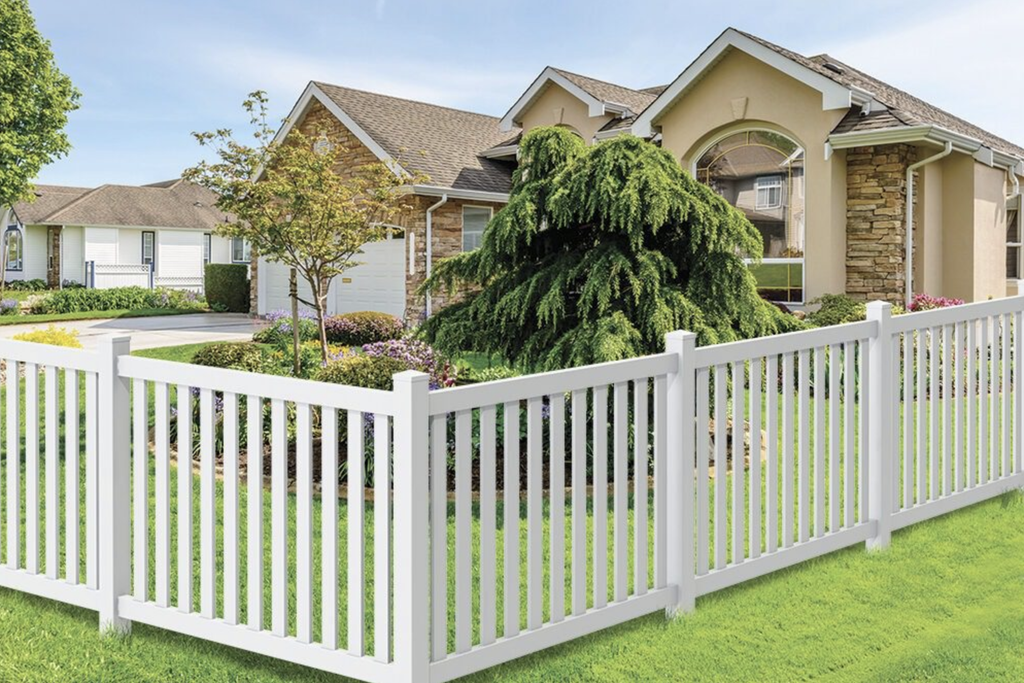 Residential home with a white picket fence, landscaped front yard, mature ornamental tree, and stone-and-stucco exterior.